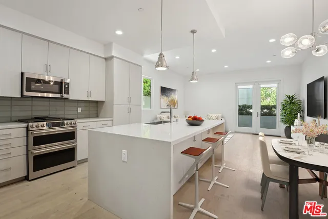 a kitchen with kitchen island a stove a table and chairs in it
