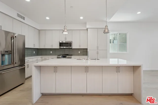 a large kitchen with kitchen island a sink stainless steel appliances and cabinets