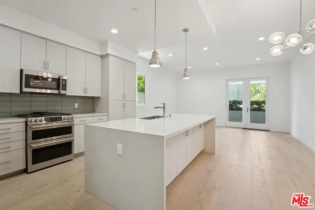 a kitchen with a sink a counter top space stainless steel appliances and cabinets