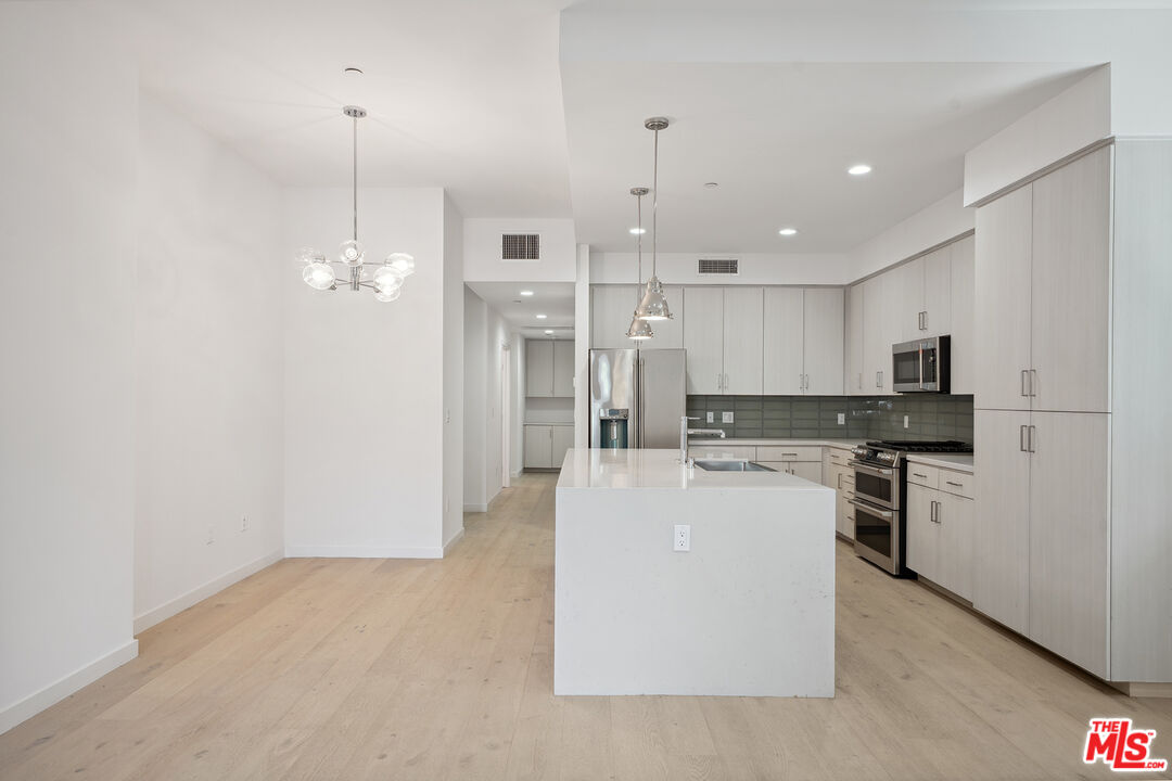 1746 Garfield Place, Unit 101 Los Angeles, CA 90028 - Photo 10 of 28 a large kitchen with kitchen island a stove a refrigerator a sink dishwasher with a dining table and chairs