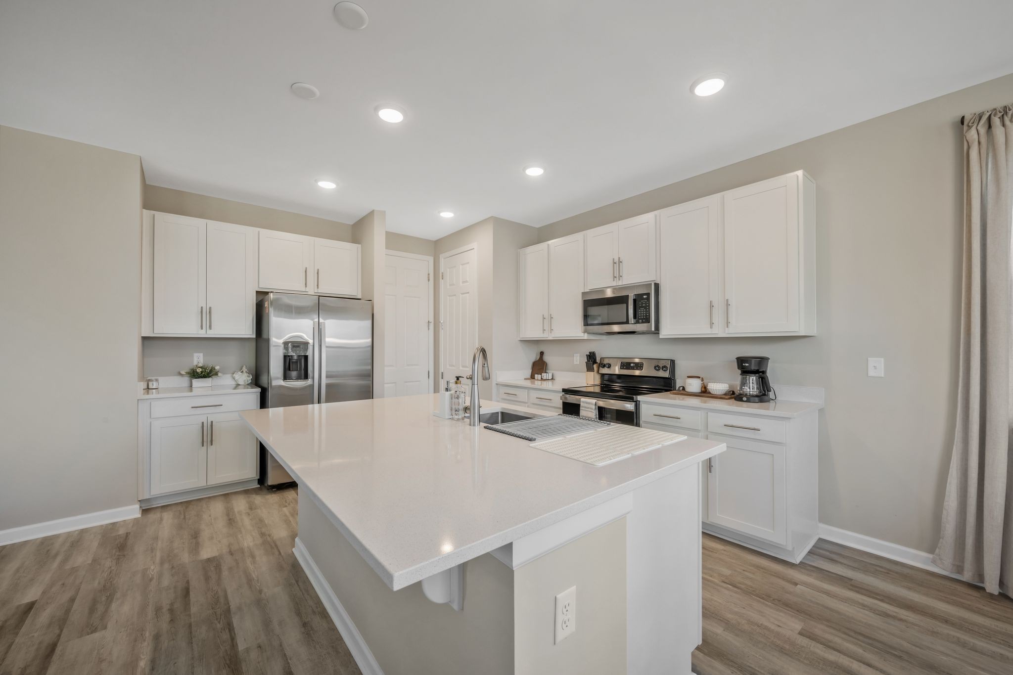 147 Timber Crest Trail White Bluff, TN 37187 - Photo 10 of 29 a kitchen with stainless steel appliances a refrigerator stove a sink and white cabinets with wooden floor