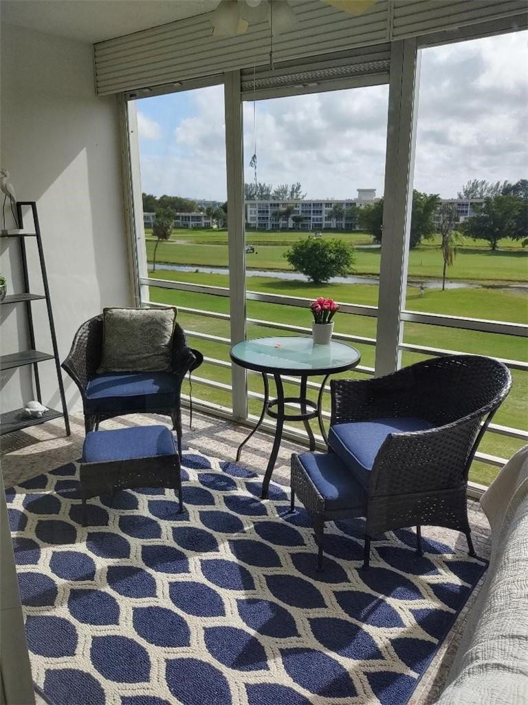 2691 South Course Drive, Unit 409 Pompano Beach, FL 33069 - Photo 2 of 22 a living room with a rug and a floor to ceiling window