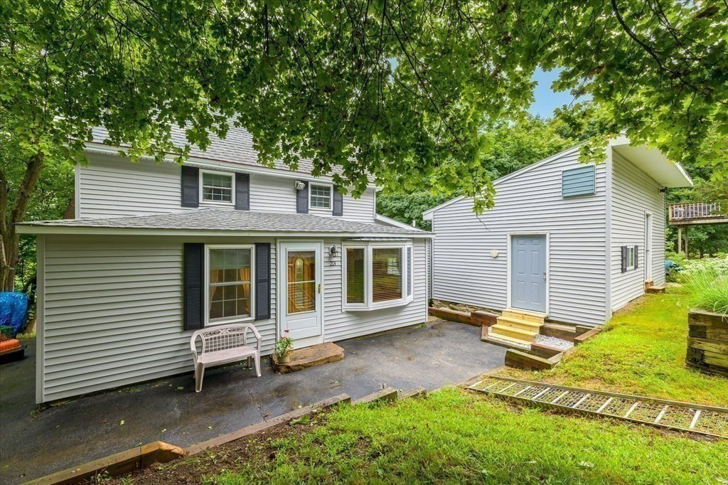 23 Mumford Road Sutton, MA 01590 - Photo 2 of 18 a view of a house with a yard and lawn chairs and a large tree