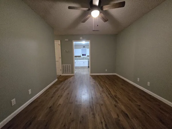 an empty room with wooden floor and windows