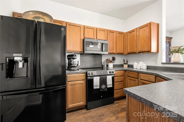 a kitchen with stainless steel appliances granite countertop a refrigerator a stove a sink and a microwave