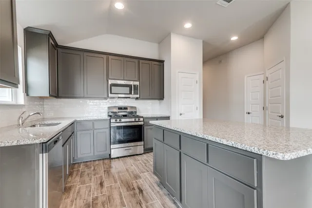 a kitchen with stainless steel appliances granite countertop a sink stove and refrigerator