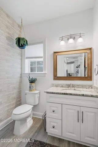 a bathroom with a granite countertop toilet sink and mirror