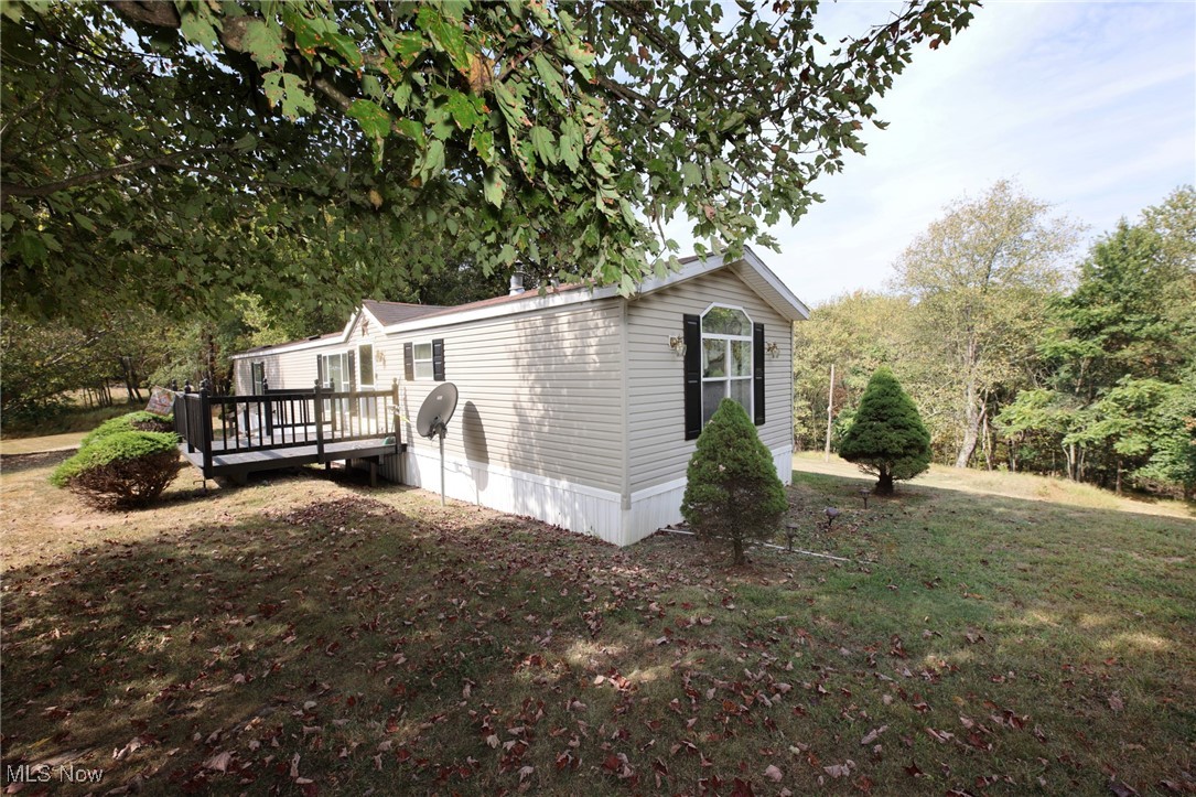 View of front of property exterior from the right hand side featuring a deck and a yard