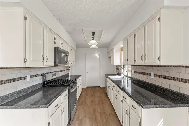 a kitchen with stainless steel appliances granite countertop a stove a sink and a refrigerator
