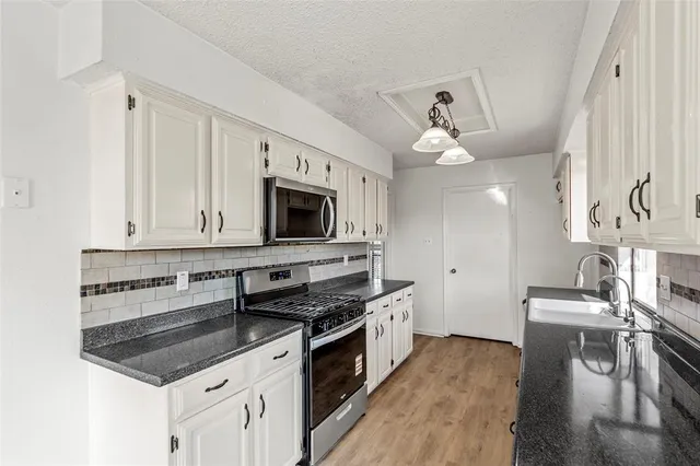 a kitchen with stainless steel appliances a stove top oven a sink and a refrigerator