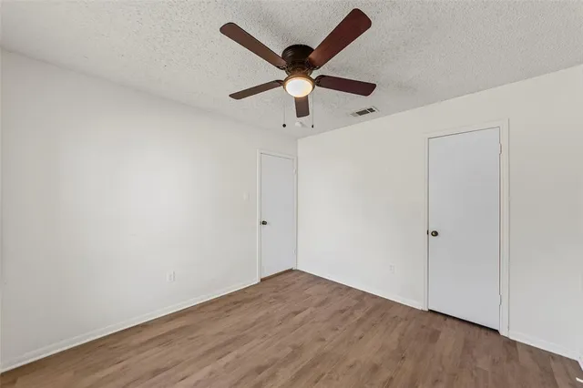 an empty room with wooden floor and ceiling fan
