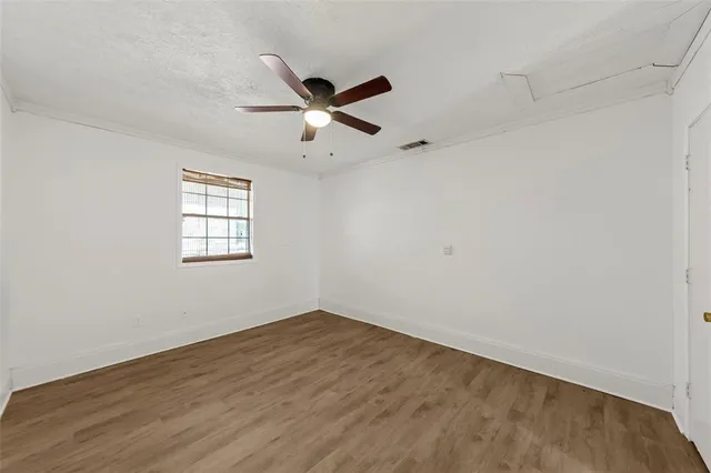 an empty room with wooden floor fan and windows