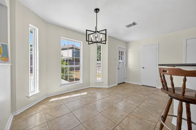 a view of an empty room with window and kitchen view