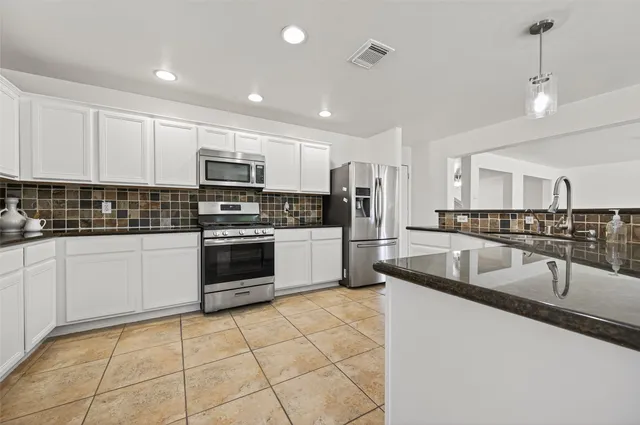 a kitchen with granite countertop a sink a counter top space appliances and cabinets