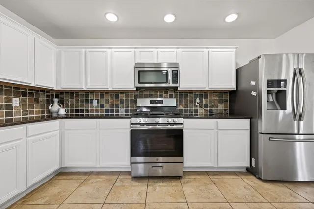 a kitchen with stainless steel appliances granite countertop a stove a refrigerator and a microwave
