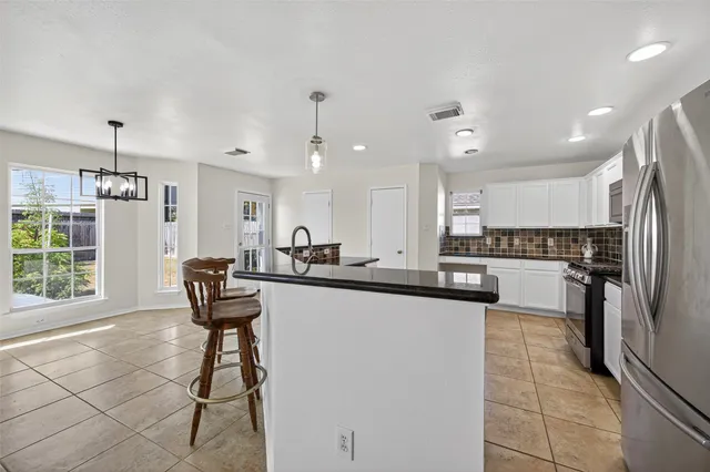 a kitchen with stainless steel appliances kitchen island granite countertop a table chairs in it and wooden floors