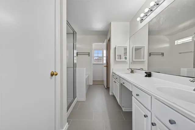a spacious bathroom with a double vanity sink a mirror and shower