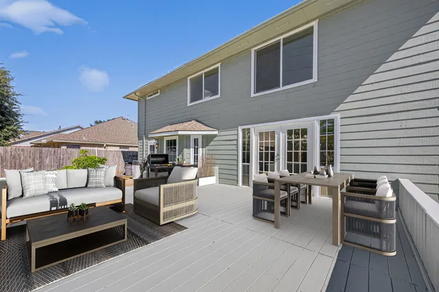 a view of a patio with couches table and chairs under an umbrella