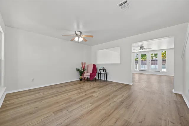 an empty room with wooden floor and chandelier fan