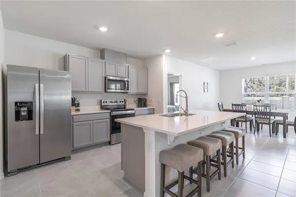 a large kitchen with cabinets chairs and refrigerator