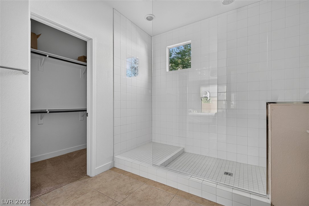 1100 East Sunset Road Henderson, NV 89011 - Photo 22 of 58 A well-lit primary bathroom features a spacious, tiled shower with a clear glass enclosure.