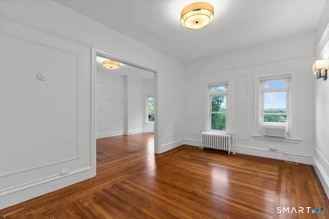 an empty room with wooden floor and window