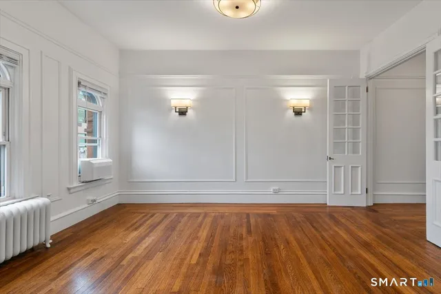 an empty room with wooden floor and windows