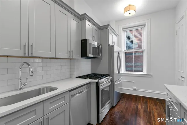 a kitchen with stainless steel appliances granite countertop a sink a stove a microwave and wooden cabinets