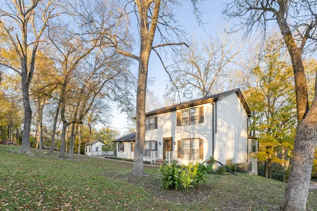 a front view of a house with a yard and large trees