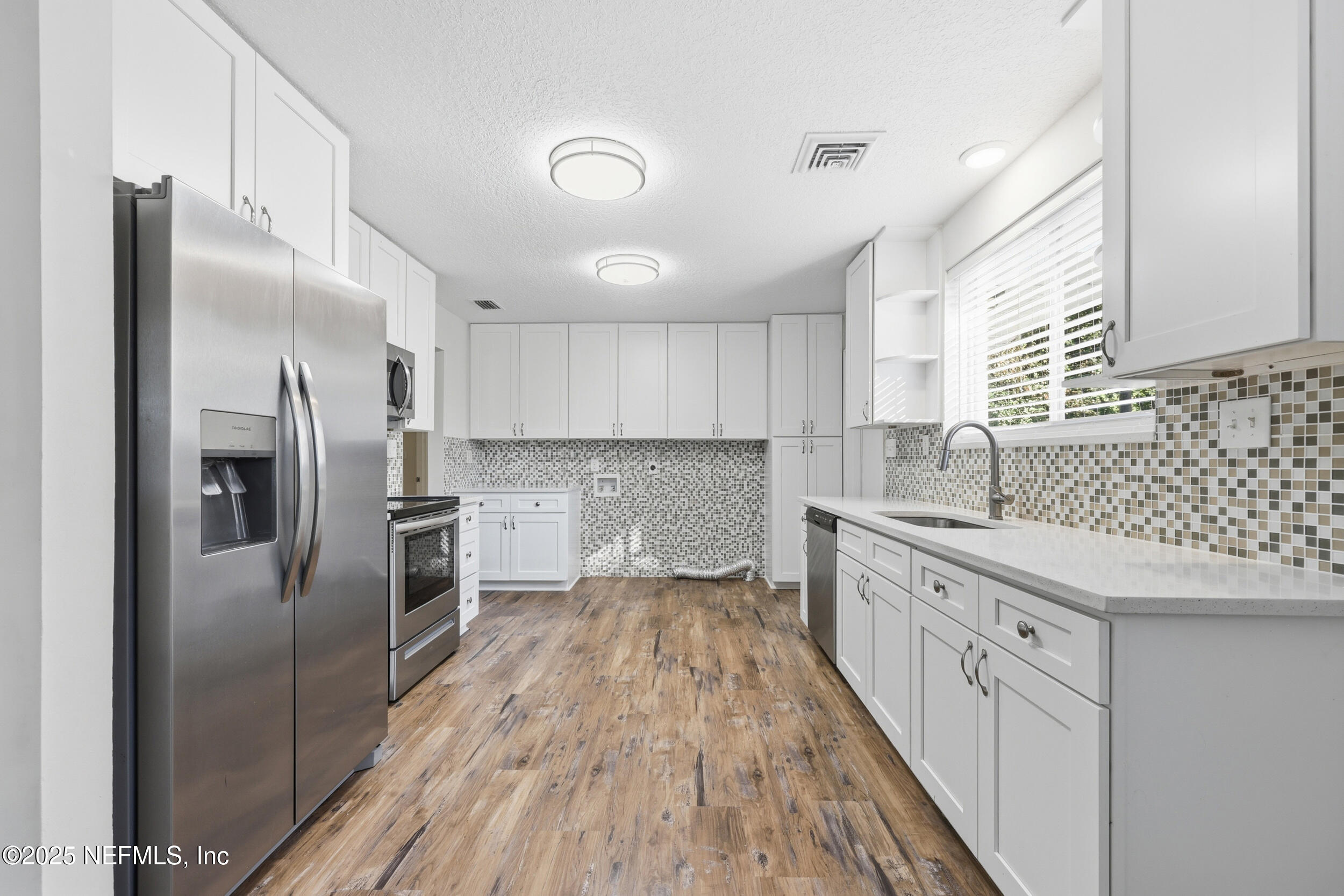 5201 Royce Avenue Jacksonville, FL 32205 - Photo 10 of 34 a kitchen with granite countertop a refrigerator oven a sink dishwasher and white cabinets with wooden floor