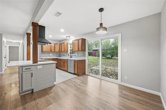 a kitchen with stainless steel appliances granite countertop a stove a sink dishwasher a refrigerator and a wooden floor