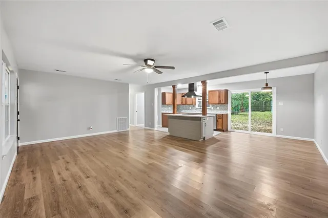 a view of a livingroom with wooden floor and a kitchen