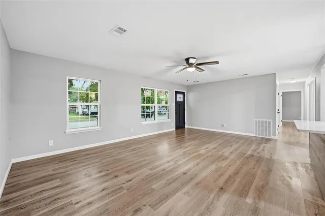 a view of an empty room with a window and wooden floor
