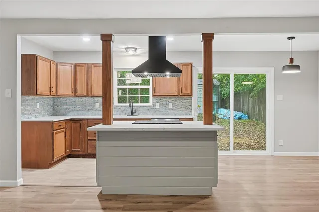 a kitchen with kitchen island a counter top a stove a sink and a large window