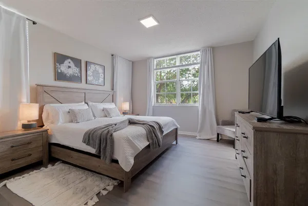 a bedroom with a bed and a flat tv screen on the dresser
