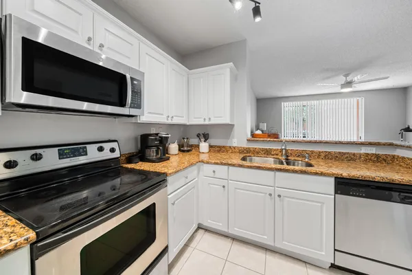 a kitchen with stainless steel appliances granite countertop a sink dishwasher a stove microwave and oven with white cabinets