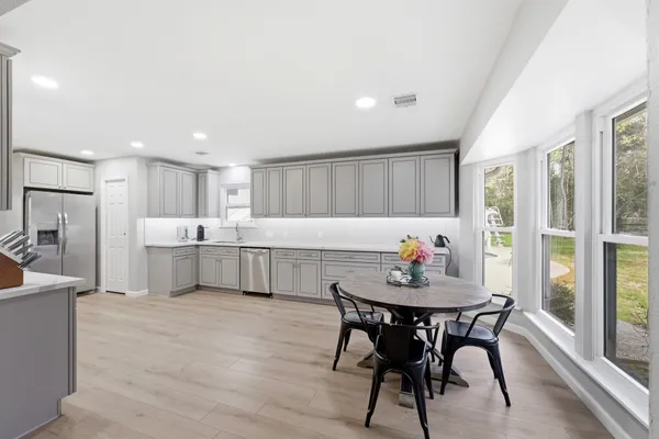 a kitchen with a dining table chairs and refrigerator