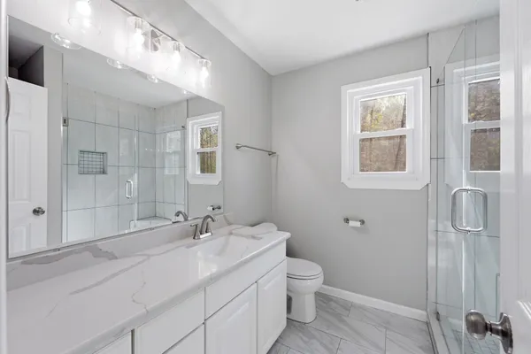 a bathroom with a granite countertop sink toilet and shower