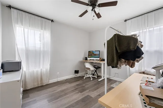 a view of empty room with wooden floor and fan