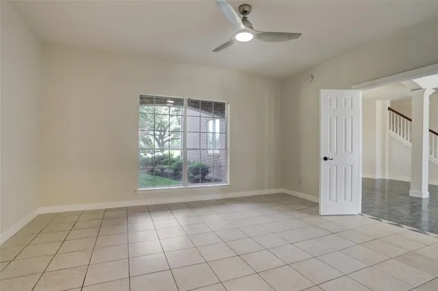 an empty room with windows and ceiling fan