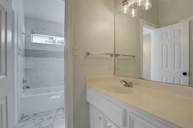 a bathroom with a tub shower vanity and a sink