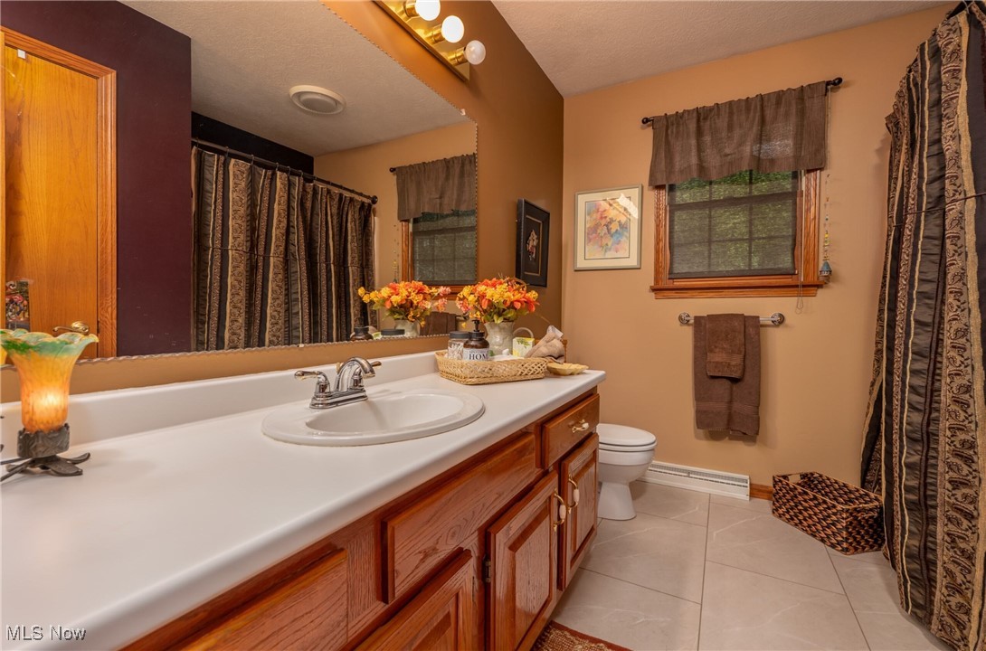 6535 Middle Run Road Dover, OH 44622 - Photo 10 of 40 Bathroom with tile patterned floors, vanity, a textured ceiling, and baseboard heating