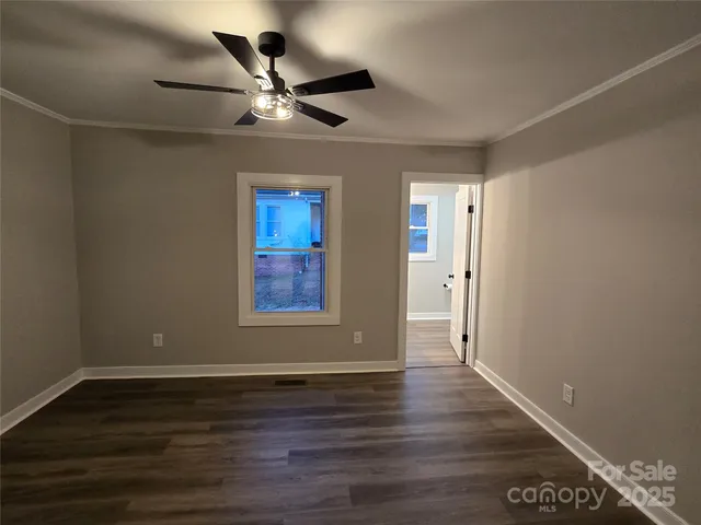 a view of an empty room with wooden floor and a ceiling fan