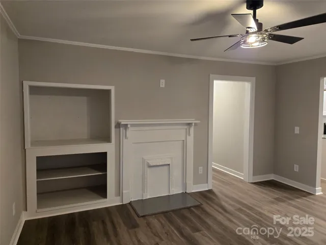 a view of an empty room with a fireplace and wooden floor