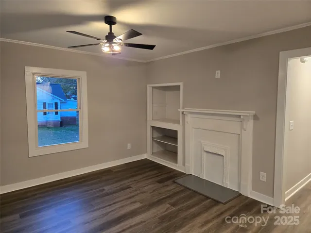 a view of an empty room with a window and wooden floor