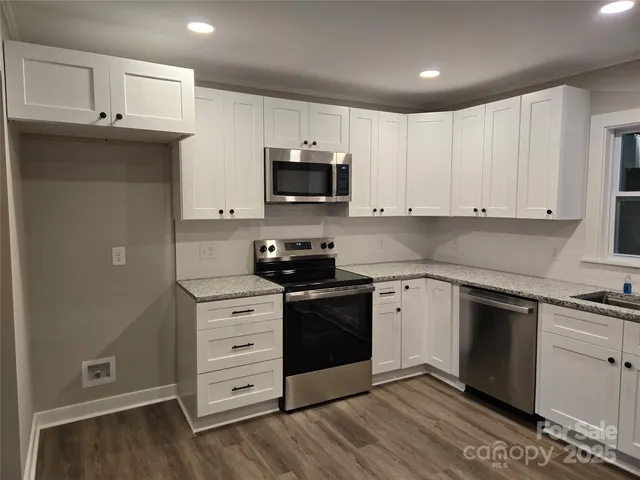 a kitchen with cabinets stainless steel appliances a sink and wooden floor