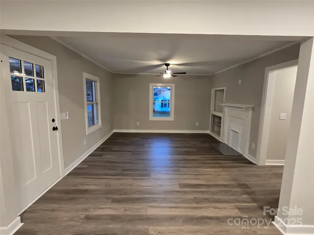 a view of an empty room with a window and wooden floor