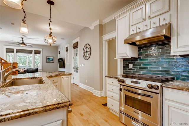 a kitchen with stainless steel appliances granite countertop a sink a stove and a wooden floor