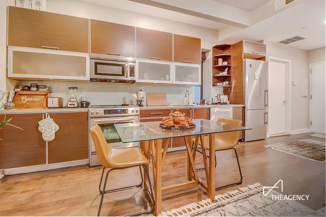 a living room with stainless steel appliances kitchen island granite countertop a dining table chairs and a refrigerator
