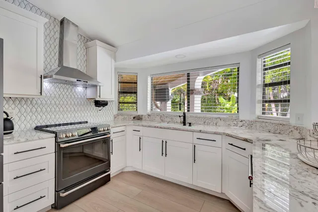 a kitchen with stainless steel appliances granite countertop a stove a refrigerator a sink a kitchen island a dining table and chairs